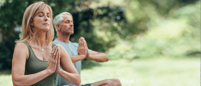 a man and a woman meditating outside